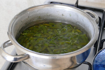 Chopped green beans are cooking in a pot, green beans are boiled in a pot, bean dish,