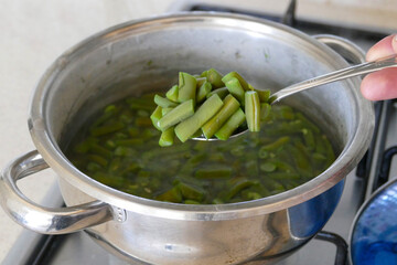 Chopped green beans are cooking in a pot, green beans are boiled in a pot, bean dish,