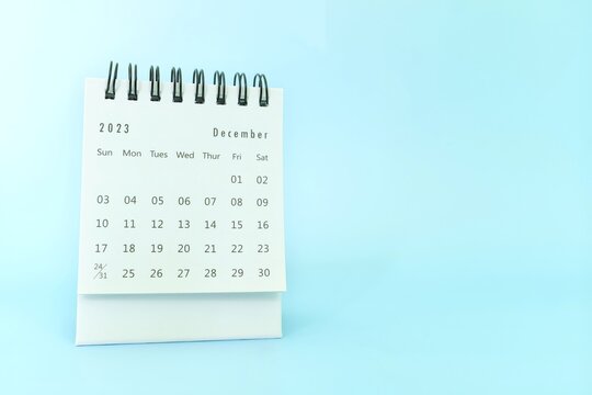 Selective focus of December 2023 desk calendar on blue background with copy space.
