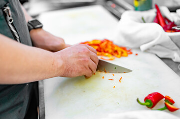 Fototapeta na wymiar chef hand Cutting red chili pepper on the cutting board in kitchen