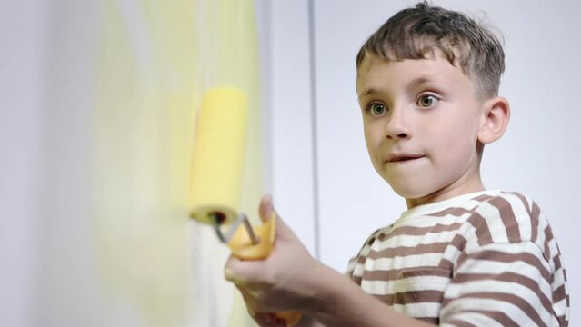 Boy painting wall for yellow paint during home renovation.