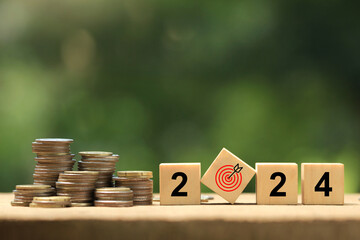 2024 New Year goal plan action. Wooden cubes with 2024 and target icon with coins stack on a green background. Business plan and development for achieving goals. Goal achievement and success in 2024.