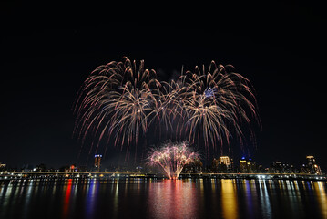 Obraz premium Colorful fireworks of various colors over night sky with reflection in water