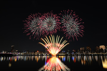 Naklejka premium Colorful fireworks of various colors over night sky with reflection in water