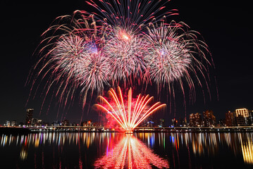 Obraz premium Colorful fireworks of various colors over night sky with reflection in water