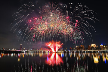 Obraz premium Colorful fireworks of various colors over night sky with reflection in water