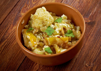 Exquisite Homemade Cauliflower and Potato Curry: A Delightful Fusion of Fresh Vegetables and Aromatic Spices, Perfectly Cooked and Served in a Rustic Ceramic Bowl on a Wooden Table
