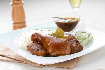 Exquisite Dining Experience: Braised Meat and Rice Served on a Square White Plate with Blue Rim, Accompanied by a Glass of White Wine and a Wooden Pepper Grinder, Set Against a Light Beige Background