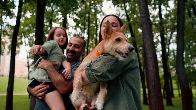 happy young family in park with dog dad holding daughter in arms concept of trust care and family values