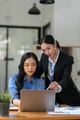 Two Asian businesswomen discuss investment project work and planning strategy Brainstorm together Find information online on iPad Laptop and tablet for making reports and summarizing business results