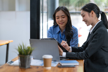 Fototapeta premium Two asian businesswoman discussing investment project work on data chart and planning strategy. About the new business in the online financial world Asian startup business ideas.