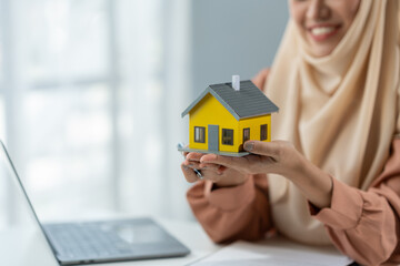 House broker representing an Asian Muslim woman presents model home plans and explains business contracts, rentals, purchases, mortgages, loans or home insurance in the office.