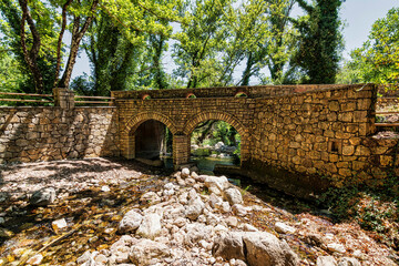 Old, stone, arched bridge across the river near Agia Theodora of Vasta church in Peloponnese, Greece.
