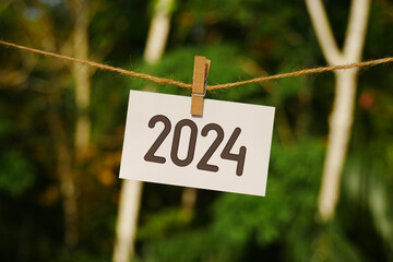 2024 on paper hanging on jute rope. Goodbye 2023 hello Happy New Year 2024 concept.