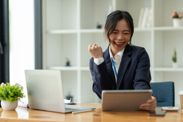 Smiling Asian business woman Delight in the achievements by using the tablet to work with plans, ideas, ideas to present. financial report business plan investment new age concept online