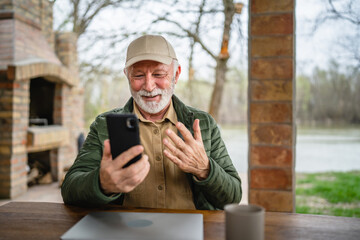 One senior man sit in front of tiny house in day use smart phone