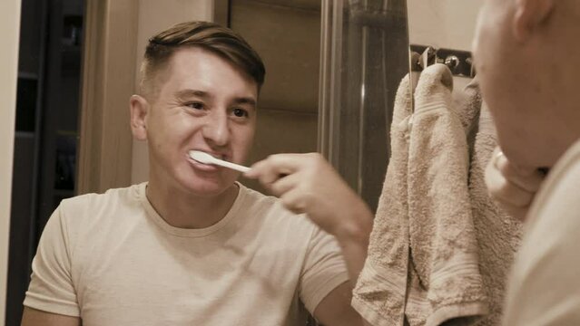 A middle-aged man brushes his teeth in the bathroom. A blond boy brushes his teeth and spits into the sink. Morning procedure. Personal Care. High quality 4k footage