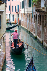 Fototapeta na wymiar Scenic view of a canal in Venice, Italy with gondola and iconic red striped shirt gondolier, Venezia Italy