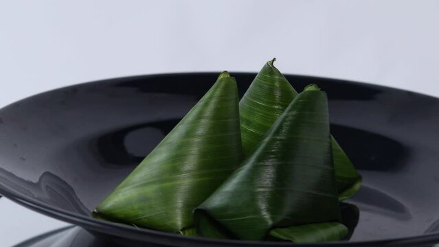 close up isolate of Kue bugis is Indonesian kue or a traditional snack of soft glutinous rice flour cake, filled with sweet grated coconut. on the black plate.
