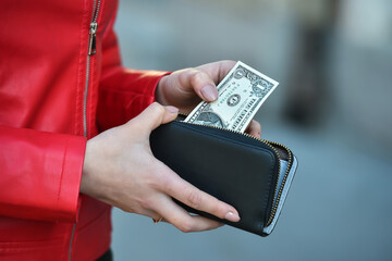 young woman hand take out one dollar bills from her wallet on street - obrazy, fototapety, plakaty