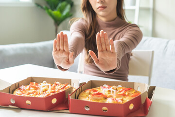 Diet concept, unhappy asian young woman, girl refusing to eat Pizza in box at home, hand pushing...
