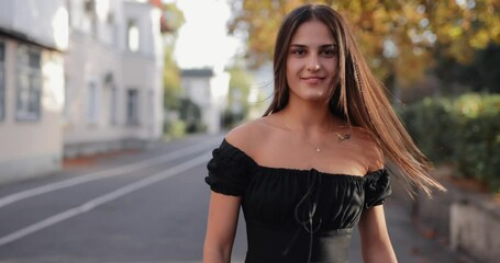 Slow motion pretty woman in dress turns face back and toss hair walking along autumn alley - Powered by Adobe