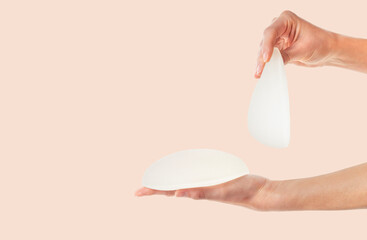 Female hands holding round and anatomical breast implants. Plastic surgery