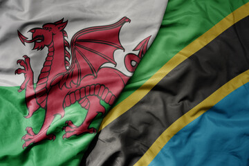 big waving national colorful flag of wales and national flag of tanzania .