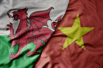 big waving national colorful flag of wales and national flag of vietnam .