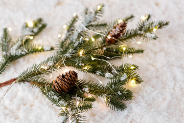 christmas, decoration and winter holidays concept - close up of fir branch with cones on artificial snow
