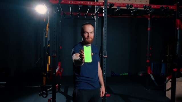 man fitness trainer shows phone with green screen sport lifestyle training technology