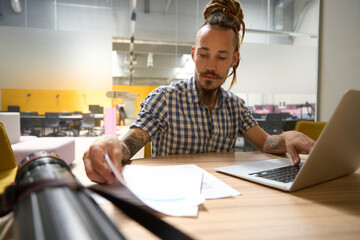 Man in a plaid shirt works with work papers