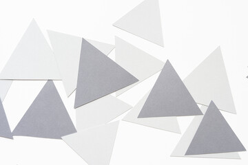 overlapping light and medium gray machine-cut triangle pieces randomly arranged on blank paper