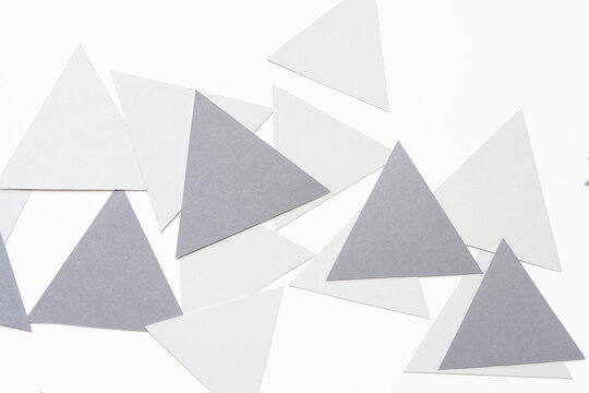 Overlapping Light And Medium Gray Machine-cut Triangle Pieces Randomly Arranged On Blank Paper