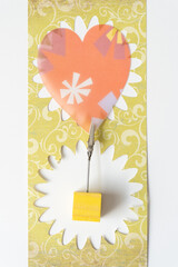 retro paper heart machine-cut from scrapbooking sheet clipped to a yellow cube and arranged on a...