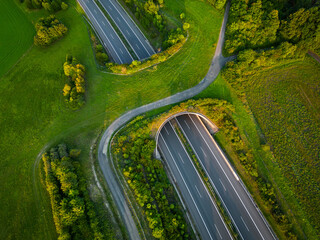 Aerial view of a green overpass over an empty highway during sunset. - 648592396