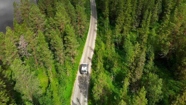 Nomad self converted off grid camper van drive on secluded forest road. 4x4 Camper with solar panels, extra tire rack and bikes on back ride on off road gravel road in Norway