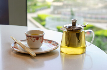 A cup of tea in a traditional Chinese teahouse, along with a teapot filled with tea