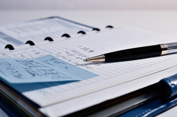  A blue notepad with sticky notes and a premium ballpoint pen