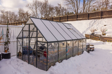 Beautiful winter view of small garden and greenhouse. Gardening concept. Sweden.