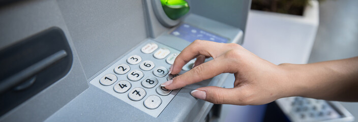 Hand entering personal identification number on ATM