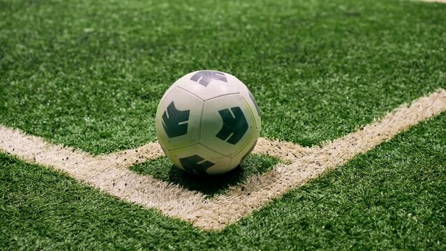 close-up of the ball standing on the corner white line marking on a soccer synthetic grass field with a rubberized