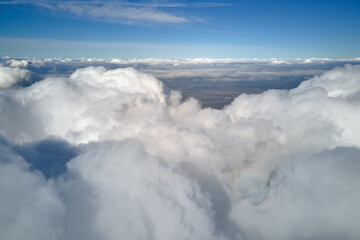 Aerial view from airplane window at high altitude of earth covered with puffy cumulus clouds...