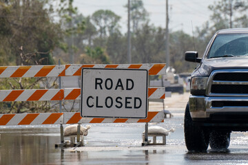 Flooded street in Florida after hurricane rainfall with road closed signs blocking driving of cars. Safety of transportation during natural disaster concept - obrazy, fototapety, plakaty
