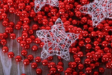Close-up of a Christmas red pearl necklace on which silver decorative stars lie on a wooden table