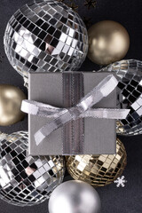 Christmas balls in gold and silver color, gift box on a black background. Christmas holiday decor.