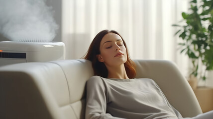 A beautiful young woman relaxed serene on comfortable sofa rest with air purifier at home. - obrazy, fototapety, plakaty