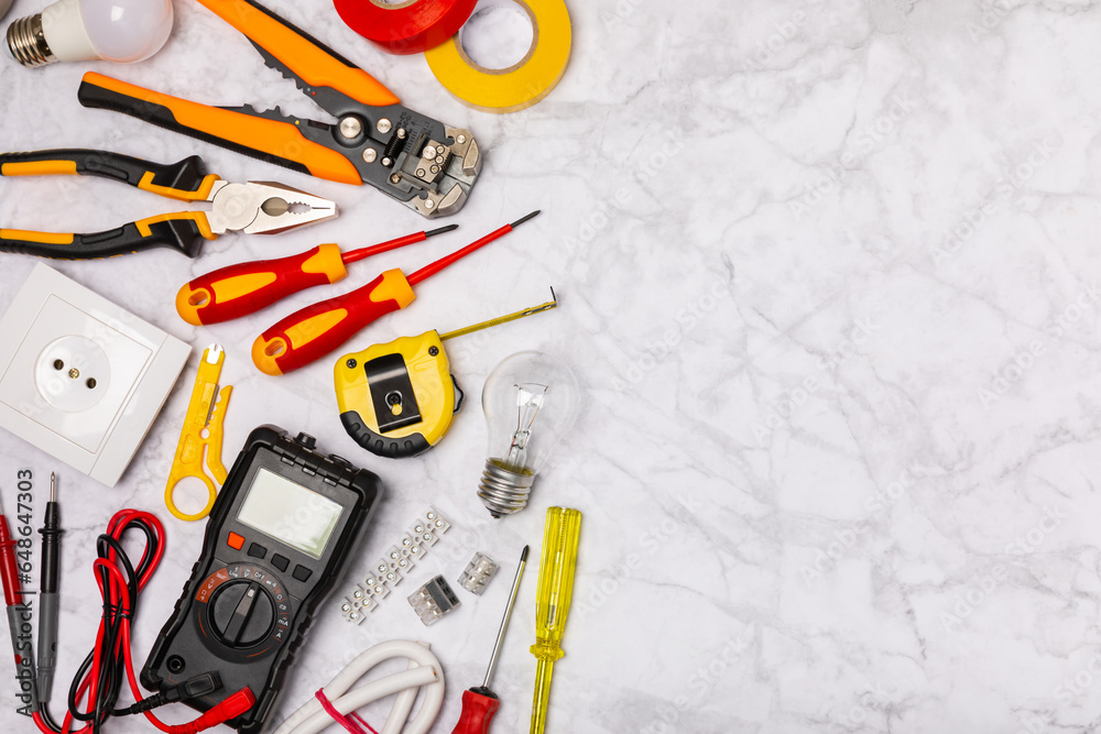 Wall mural Electrician tools on light background.Multimeter,construction tape,electrical tape, screwdrivers,pliers,an automatic insulation stripper, socket and LED lamp.Flatley.electrician concept.