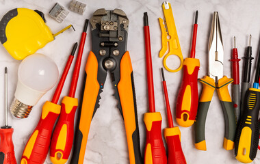 Electrician tools on light background.Multimeter,construction tape,electrical tape, screwdrivers,pliers,an automatic insulation stripper, socket and LED lamp.Flatley.electrician concept.