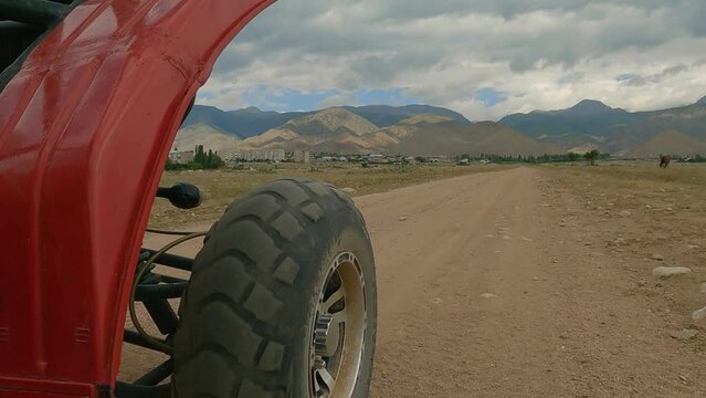 The front wheel of the buggy rides on a road. Rear side view.  Quad buggy vehicles race, extreme sports transport, driving off-road.  4wd buggy atv utv adventure. Buggy extreme ride 